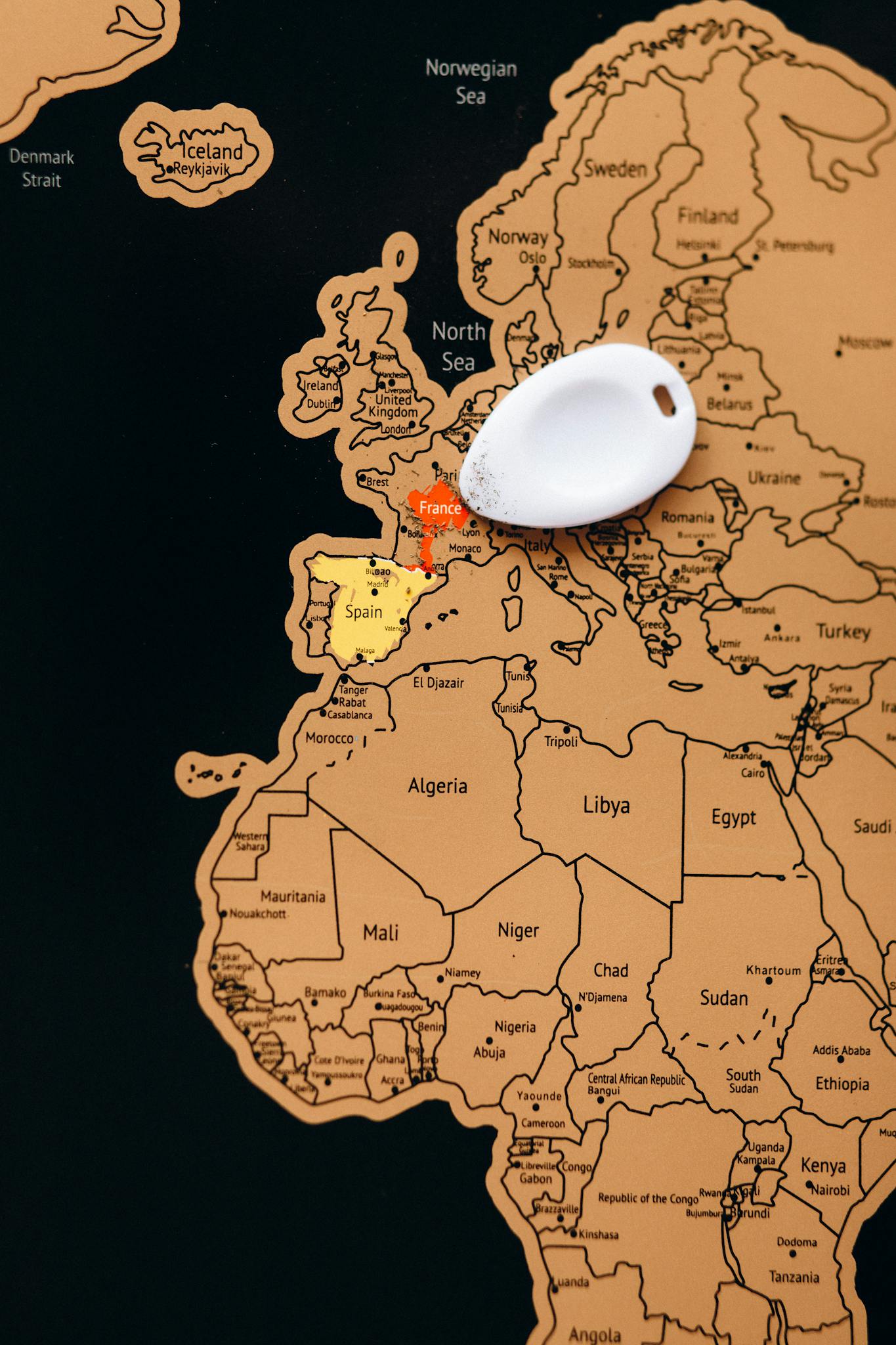Close-up view of Europe on a scratched travel map with a key tag marking locations.